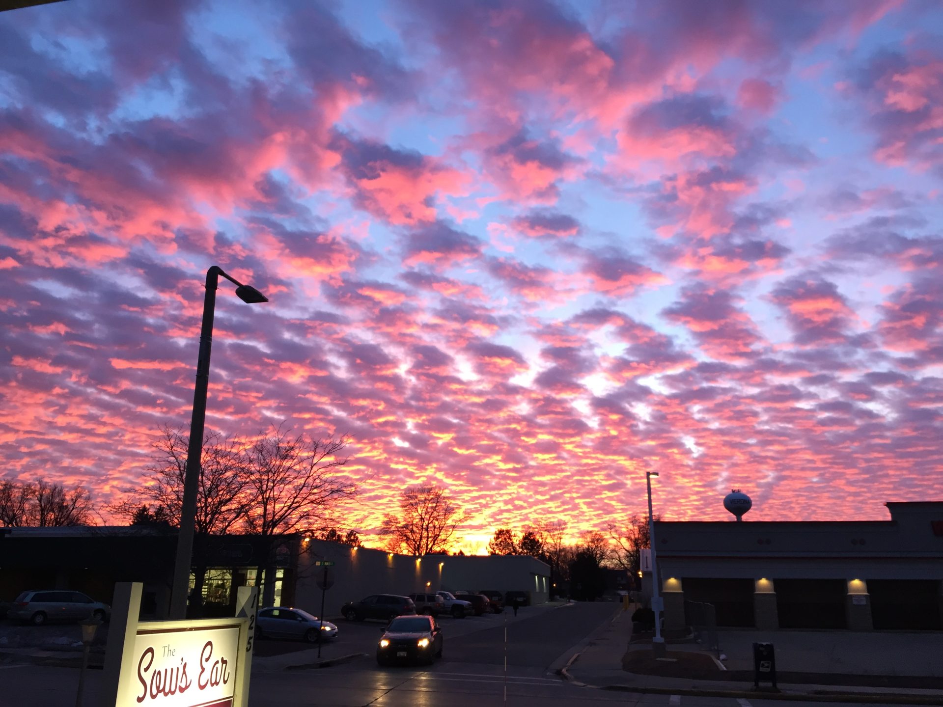 a dramatic sunset lights up the clouds pink and gold over Verona, with The Sow's Ear sign visible in the lower left corner.